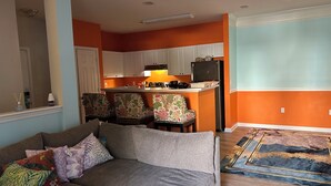A living room with a sofa, chairs, and a kitchen area with cabinets and appliances. - Bright apartment in a superb Virginia Beach location with AC (Virginia Beach)