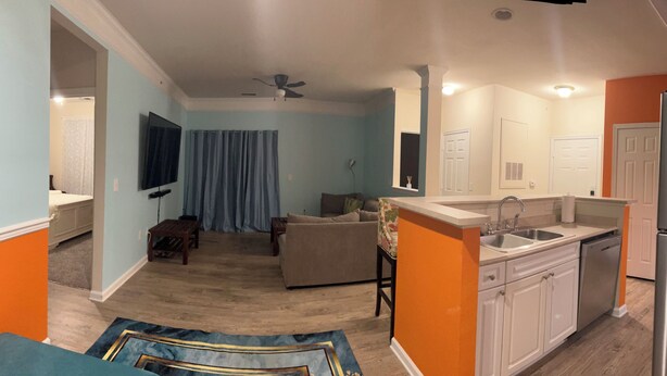 A living room with a sofa, a coffee table, and a TV. There is a kitchen with a sink, a refrigerator, and cabinets. - Bright apartment in a superb Virginia Beach location with AC (Virginia Beach)