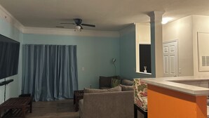 A living room with a sofa, a TV, a ceiling fan, and a window with a view. - Bright apartment in a superb Virginia Beach location with AC (Virginia Beach)