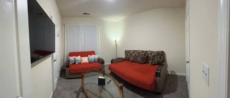 A compact room with two sofas, a small table, a television, and a ceiling light.