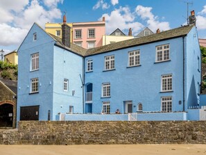 Un immeuble à plusieurs étages, doté d’une façade bleue, d’un mur en pierre et d’une clôture blanche en bois.