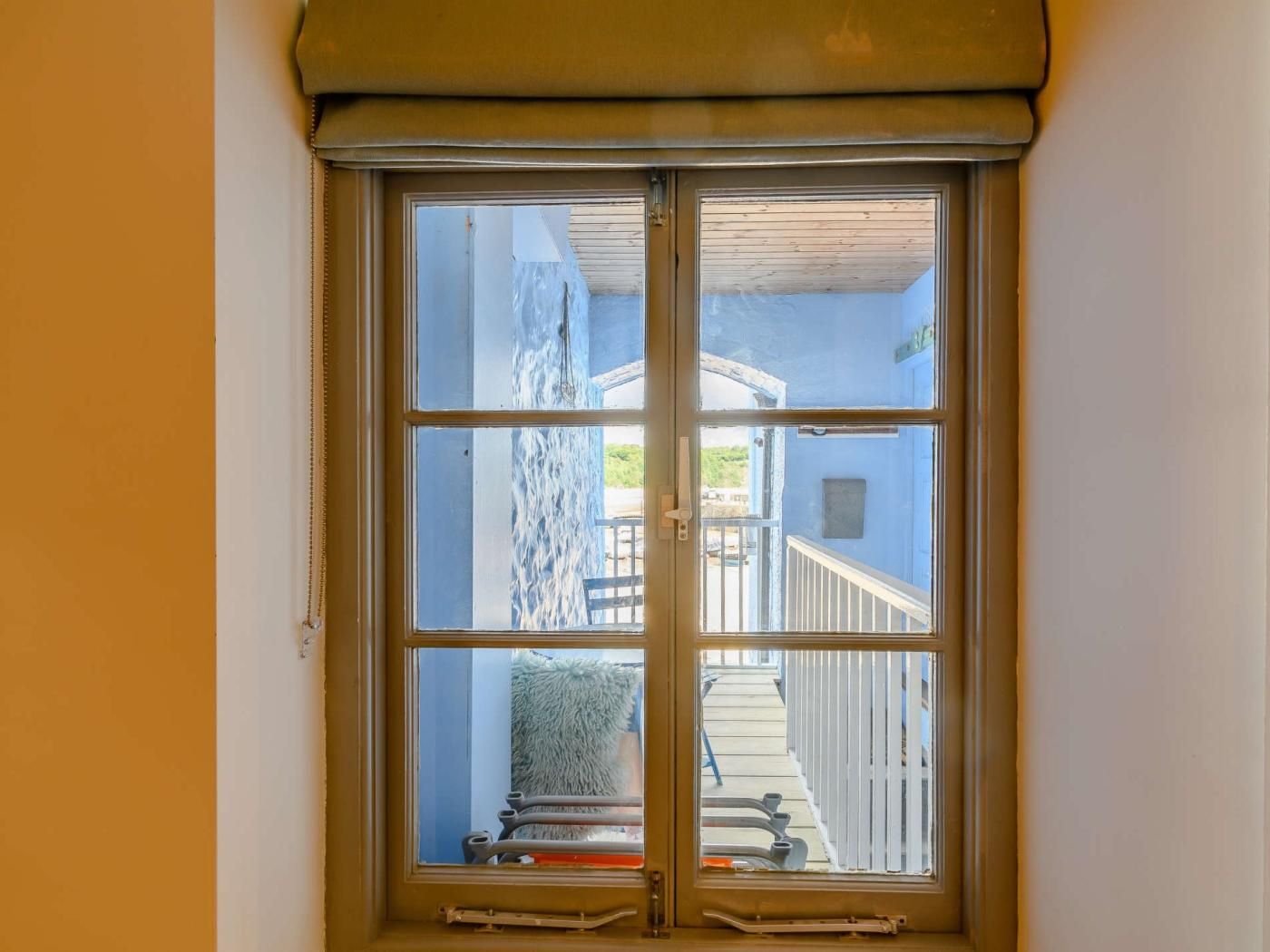 Une fenêtre donnant sur la façade d’un immeuble, avec vue sur un escalier et des garde-corps.