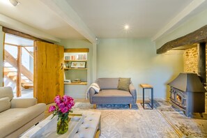 A cozy living room with a sofa, a coffee table with flowers, a fireplace, and a bookshelf. - 3 Bed in Beaminster (oc-87914) (South Perrott)