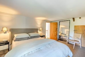 A bedroom with a large bed, bedside lamps, a wooden door, a chair, and a mirror. - 3 Bed in Beaminster (oc-87914) (South Perrott)