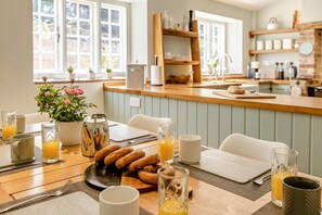 A breakfast setting with a table, breakfast items, and a kitchen area with shelves and a window. - 3 Bed in Beaminster (oc-87914) (South Perrott)