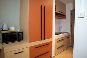A compact kitchen with a microwave, a kettle, and a sink.