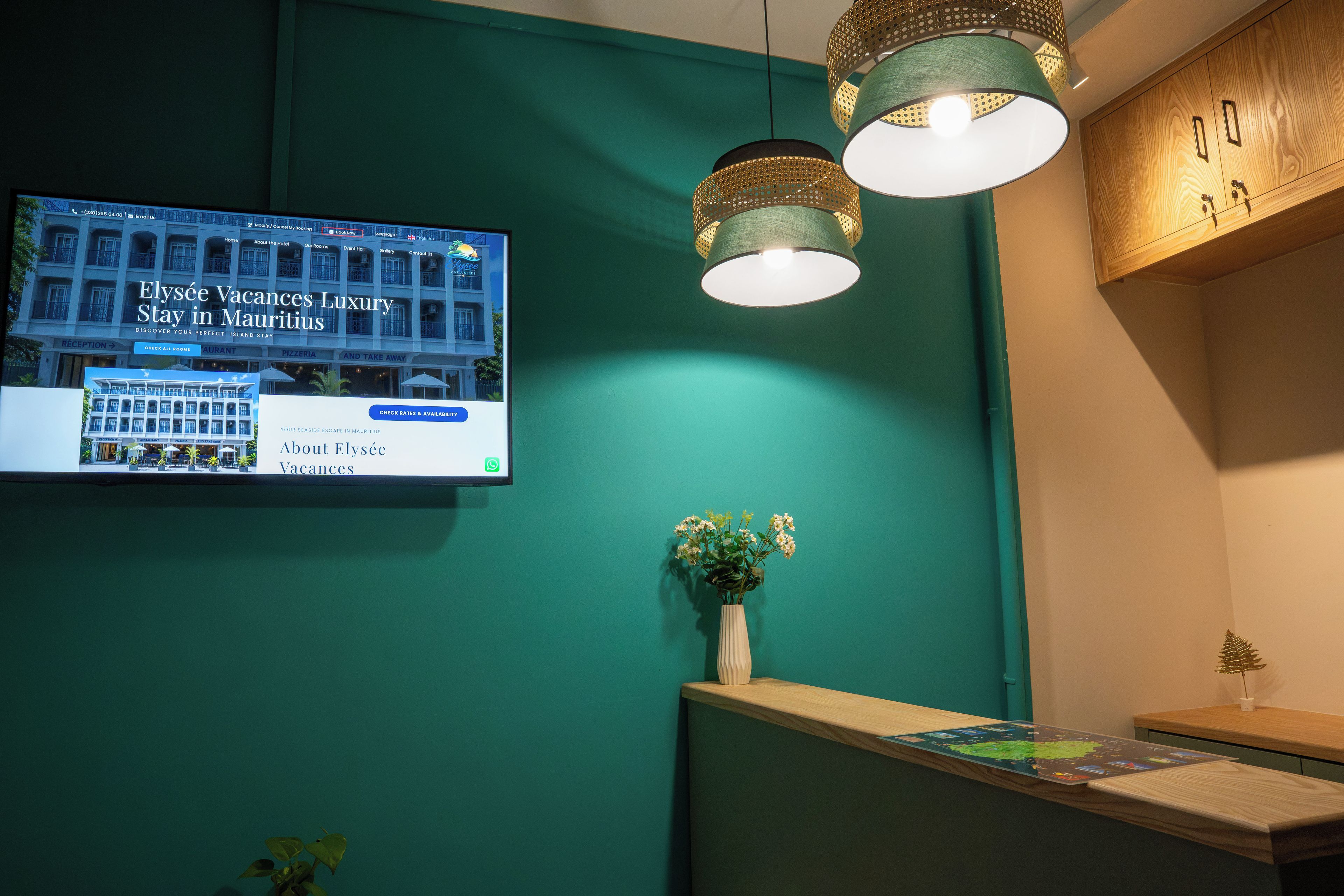Una zona de recepción con una pantalla digital, un mostrador de madera y una pared verde.