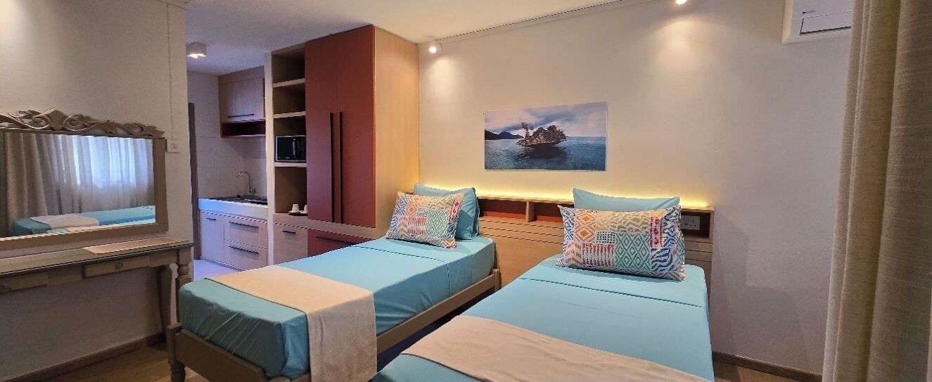 Een hotelkamer met twee bedden, een spiegel, een schilderij en een kledingkast.