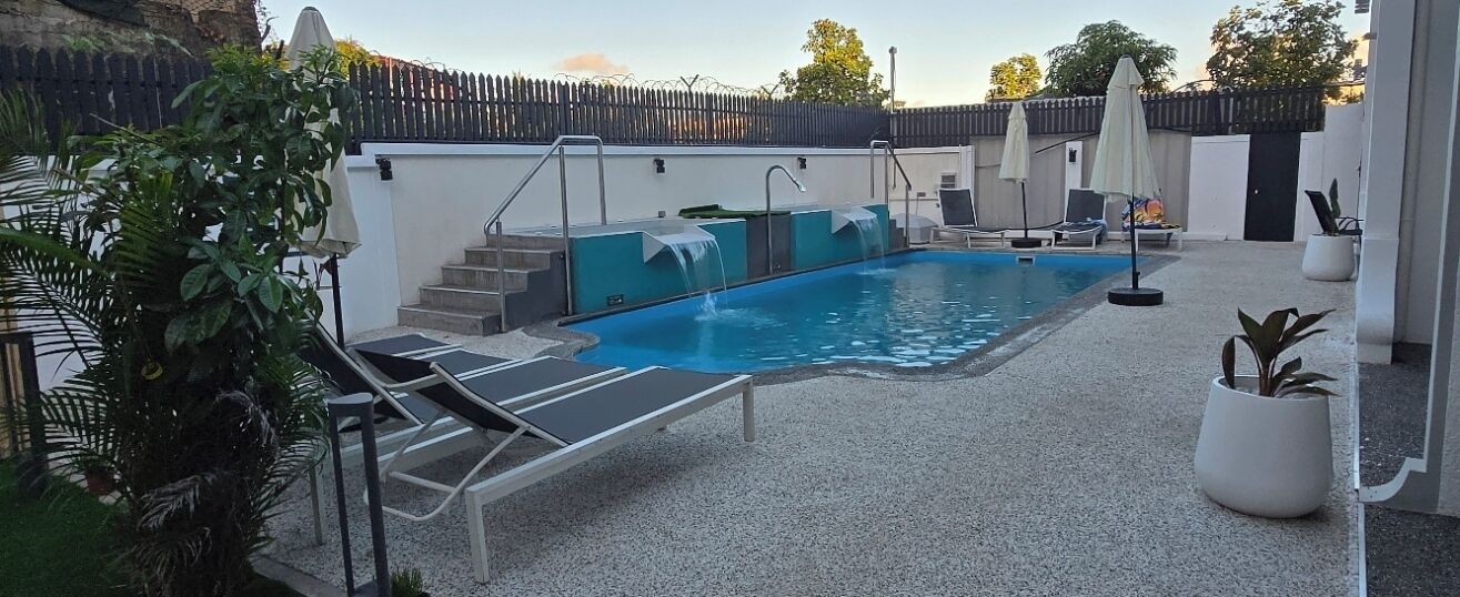 A swimming pool with steps leading into it, surrounded by lounge chairs and umbrellas.