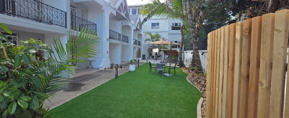 Un patio con césped verde, mobiliario exterior y cerca de madera.