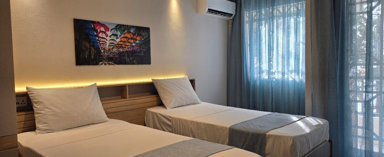 Een hotelkamer met twee bedden, een schilderij aan de muur en een airconditioning.