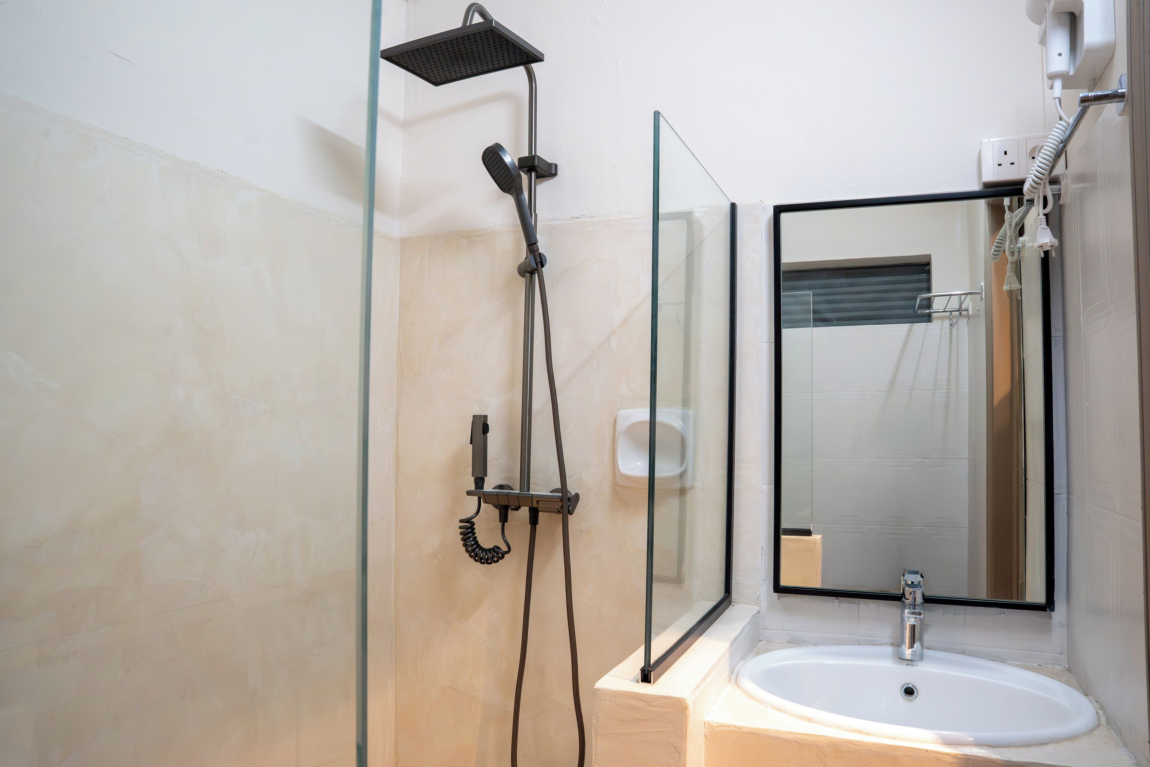 Une salle de bain avec une douche à parois de verre, un lavabo blanc et un miroir.