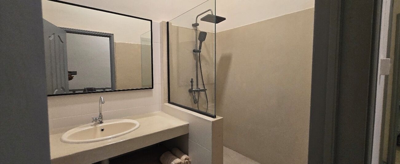 A bathroom with a sink, mirror, and glass-enclosed shower.