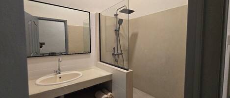 A bathroom with a sink, mirror, and glass-enclosed shower.
