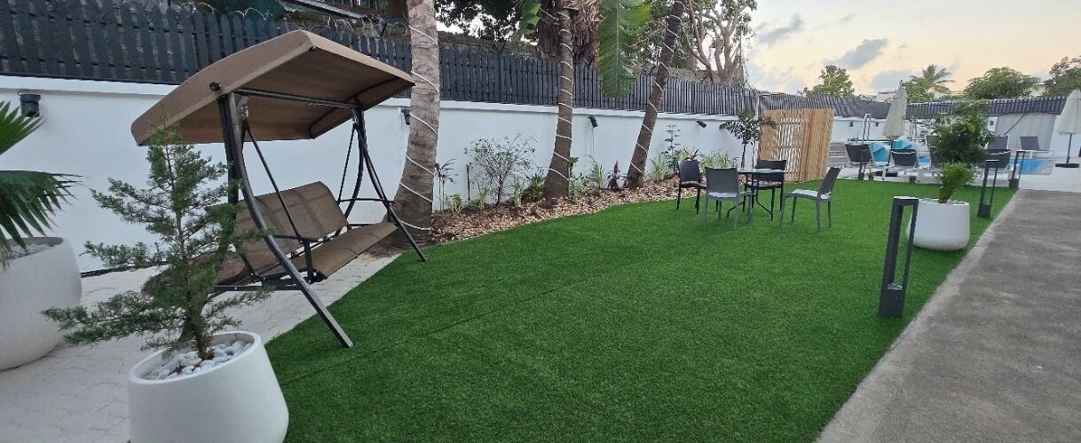 A patio area with artificial grass, outdoor furniture, and a swing set.