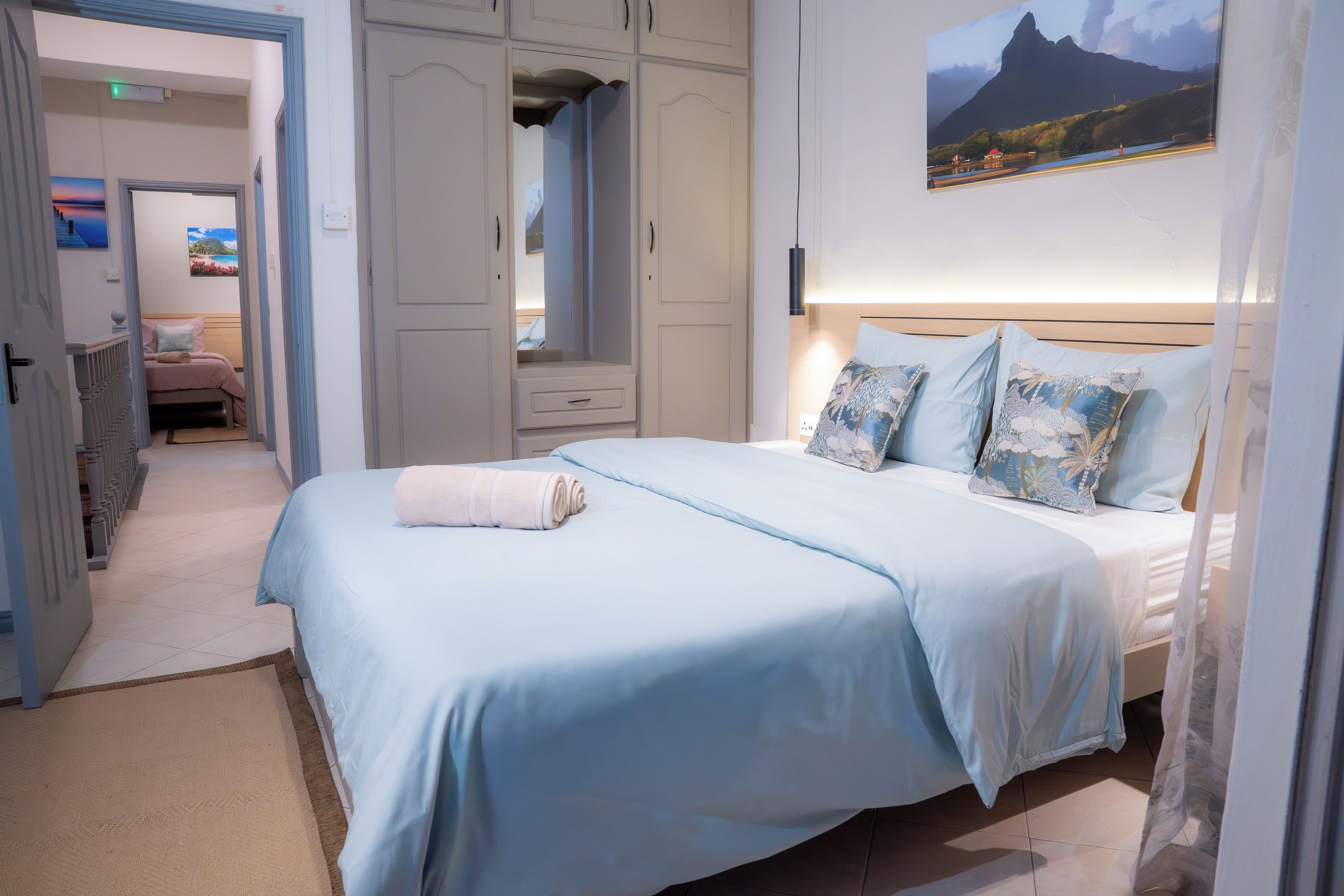Una habitación de hotel con una cama, un armario, un espejo y un cuadro en la pared.