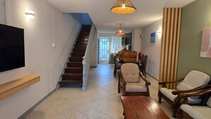 A living room with a TV, wooden furniture, a staircase, and a dining area.