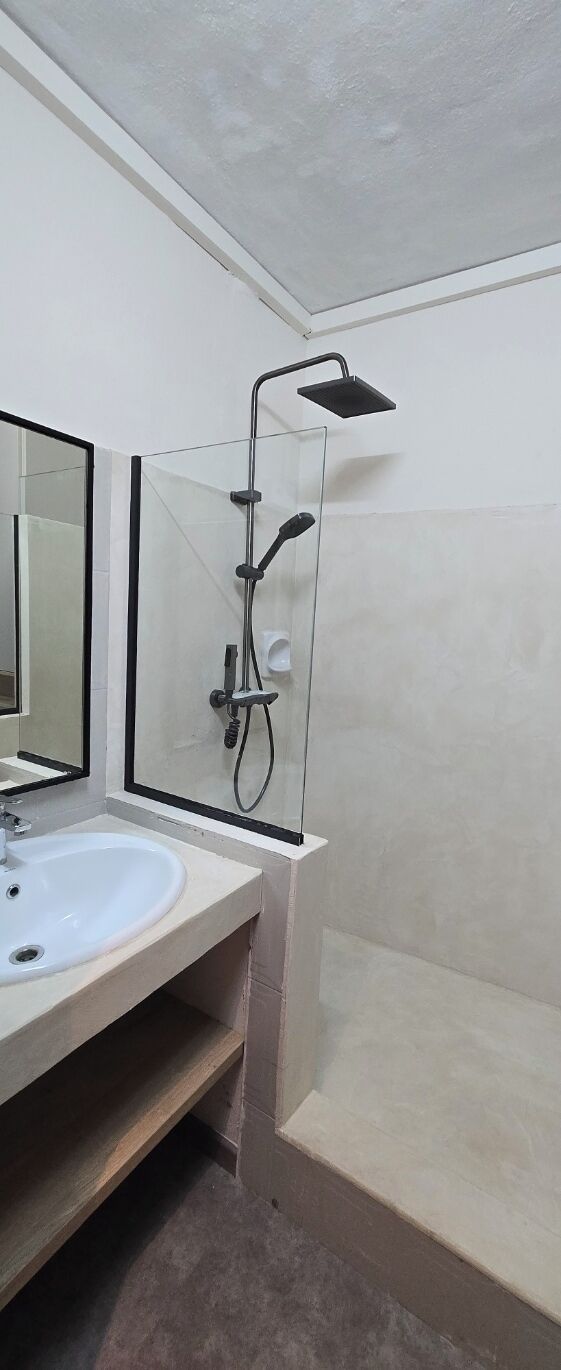 A bathroom with a white sink, a glass shower enclosure, and a mirror.