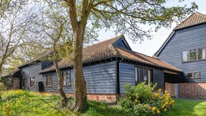 A two-story house with a dark wooden exterior, a brick foundation, and a tiled roof. - 2 Bed in Aldham (oc-87956) (Aldham)