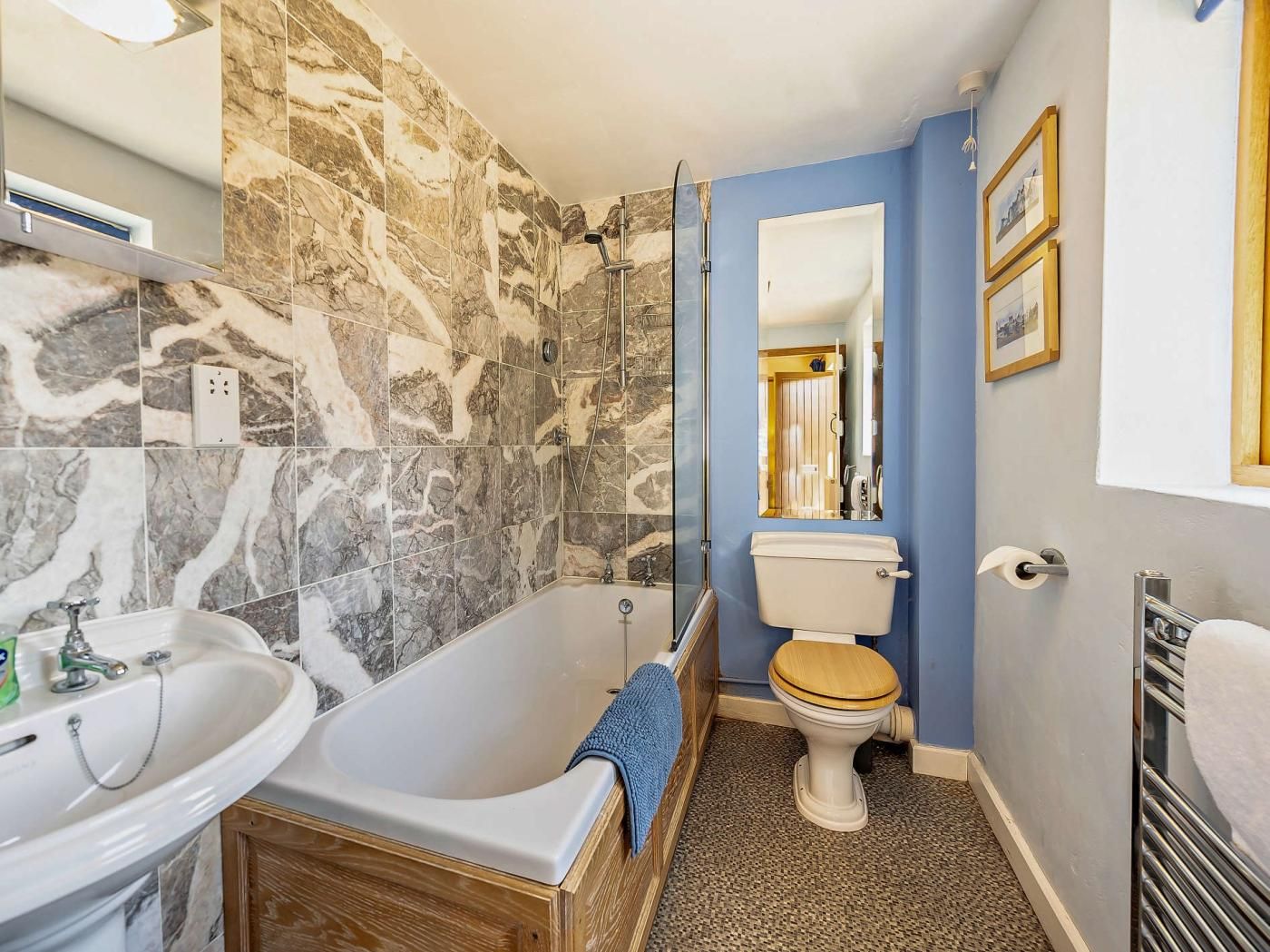 A bathroom with a bathtub, sink, toilet, and marble walls.