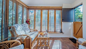 A spacious room with a large window, wicker furniture, and a view of greenery outside. - 2 Bed in Aldham (oc-87956) (Aldham)