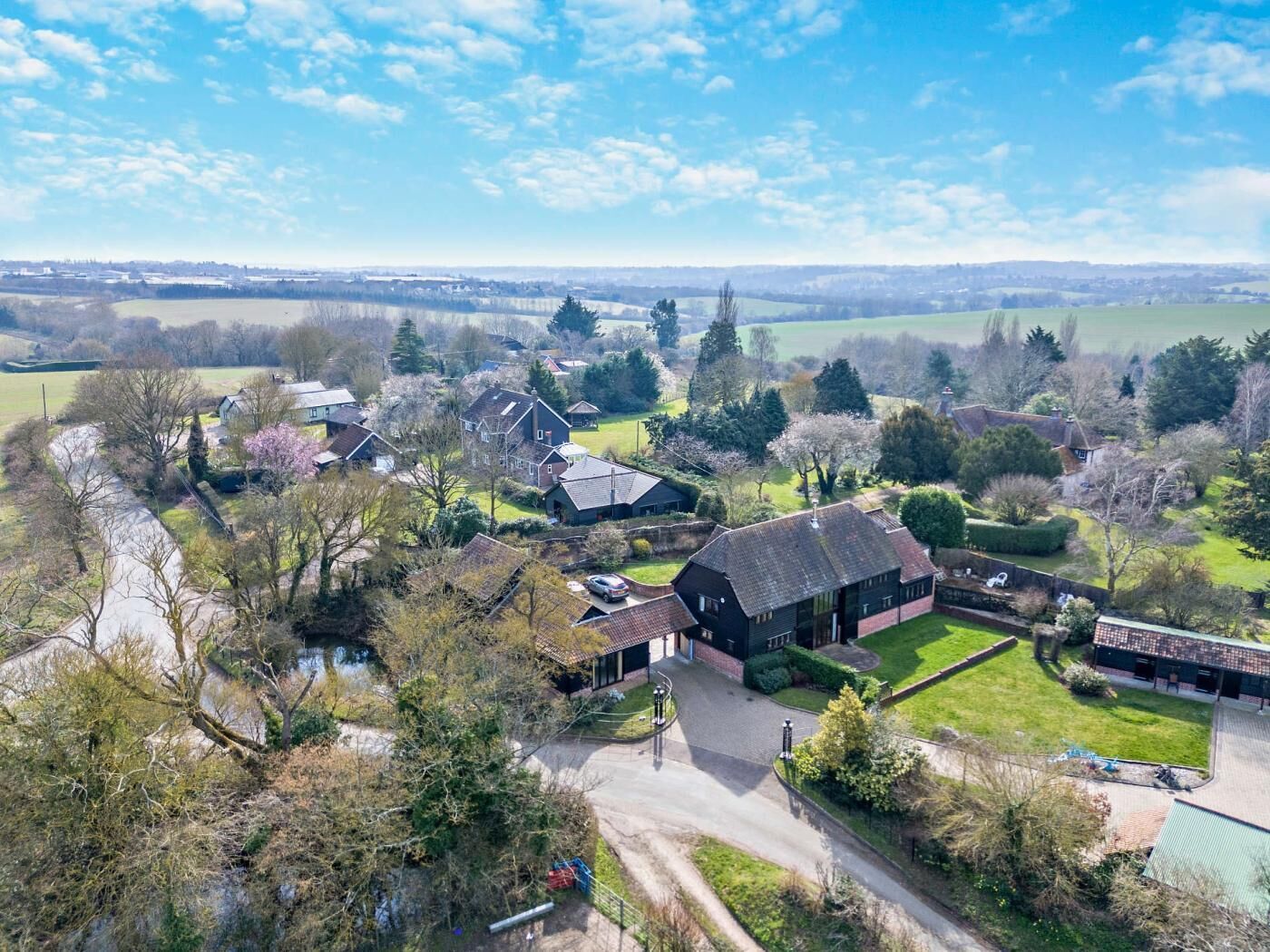 Vista aérea de una zona residencial con casas, un granero y un campo verde.