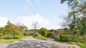 A rural road flanked by greenery and trees, leading to a residential area. - 2 Bed in Aldham (oc-87956) (Aldham)