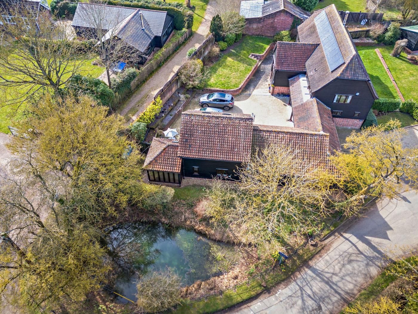 Een woonwijk met huizen, een oprit en een kleine vijver.