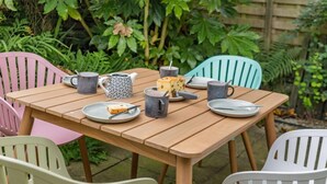 A wooden table set with plates, mugs, and a teapot in a garden with chairs. - 3 Bed in Ulverston (oc-87960) (Penny Bridge)