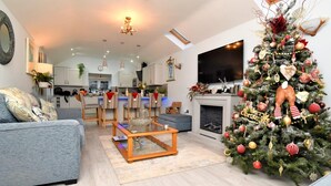 Ein modernes Wohnzimmer mit Kamin, einem großen Weihnachtsbaum und einem Fernseher.