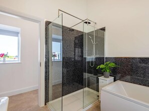 Ein modernes Badezimmer mit einer gläsernen Dusche, einer weißen Badewanne und einem Blumentopf.