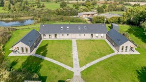 A large, modern building with a symmetrical design, featuring a central courtyard and a surrounding lawn.