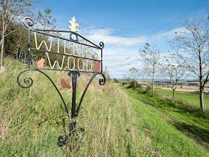 A metal sign with the inscription 'WILD WOOD' in a rural setting. - 3 Bed in St. Andrews (oc-88420) (Balmullo)