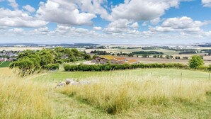 Ländliche Landschaft mit einem Haus, umgeben von Feldern und Bäumen.