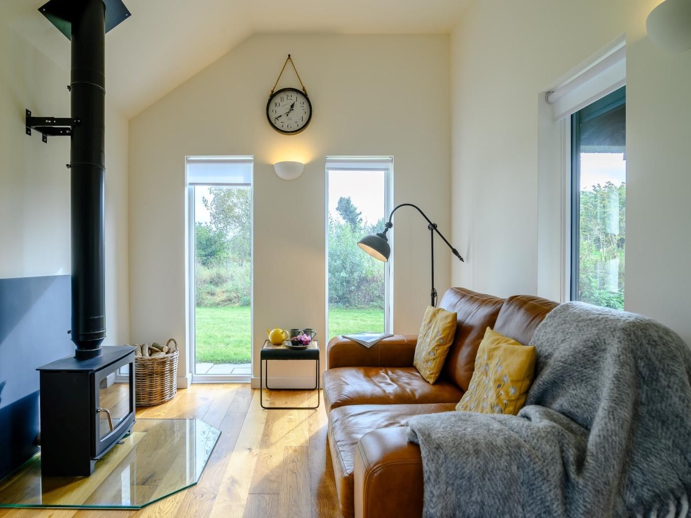 A living room with a fireplace, a sofa, a lamp, and a view of the outdoors.