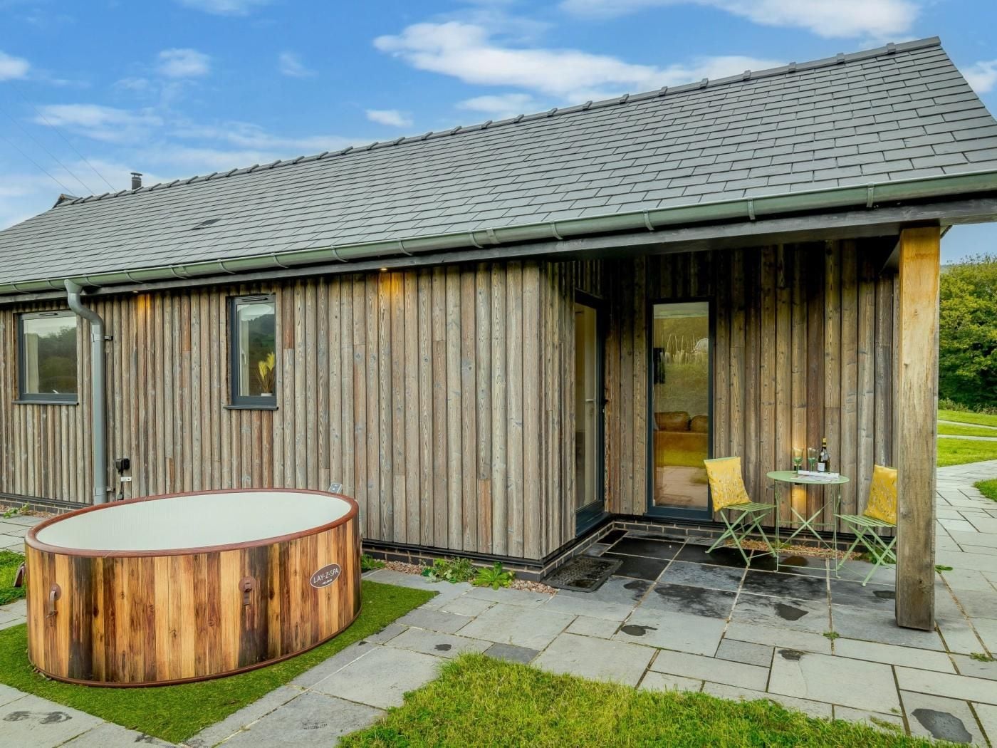 A wooden cabin with a hot tub and a patio area.