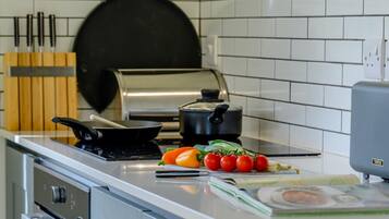 A kitchen with a stove, a frying pan, a pot, and some vegetables on the counter.