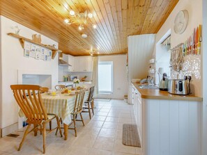 A kitchen with wooden ceiling, a dining table with chairs, a refrigerator, and a wall-mounted knife rack. - 3 Bed in Bideford (oc-88143) (Hartland)
