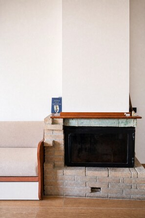 A fireplace with a brick surround, a wooden mantel, and a book titled 'Storia di Sardegna' on it. - Casa della Ceramica, a cozy, newly renovated apartment. (Cagliari)