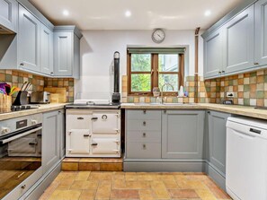 A kitchen with grey cabinets, a stove, a sink, and a window with a view of greenery. - 3 Bed in Hereford (oc-88077) (Clyro)