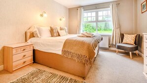 Een slaapkamer met een bed, nachtkastjes, een stoel, een raam en een radiator.