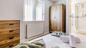 Un dormitorio con cama, armario de madera, radiador y ventana con persianas.