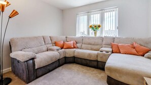 Una sala moderna con un sofá modular, una lámpara de pie y un jarrón con flores.