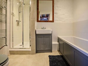 Een badkamer met een douchecabine van glas, een wastafel en een bad.