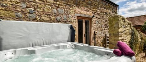 A stone building with a hot tub in front.