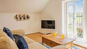 Una sala de estar con sofá, mesa de centro, televisor y ventana con vistas.