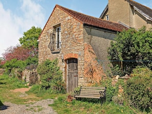 Edificio de piedra con puerta de madera y balcón.