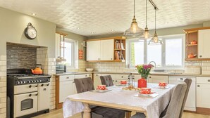 Una cocina con estufa, horno y mesa de comedor dispuesta para una comida.