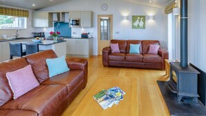 Eine moderne Küche mit Kochinsel, ein Wohnzimmer mit Ledersofas und ein Kaminofen.