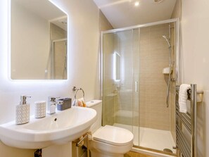 Un bany modern amb dutxa de vidre, un lavabo blanc i un vàter.